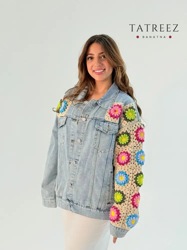 Handmade crochet jeans jacket featuring vibrant flowers in light colors, showcasing unique craftsmanship and artistic design.