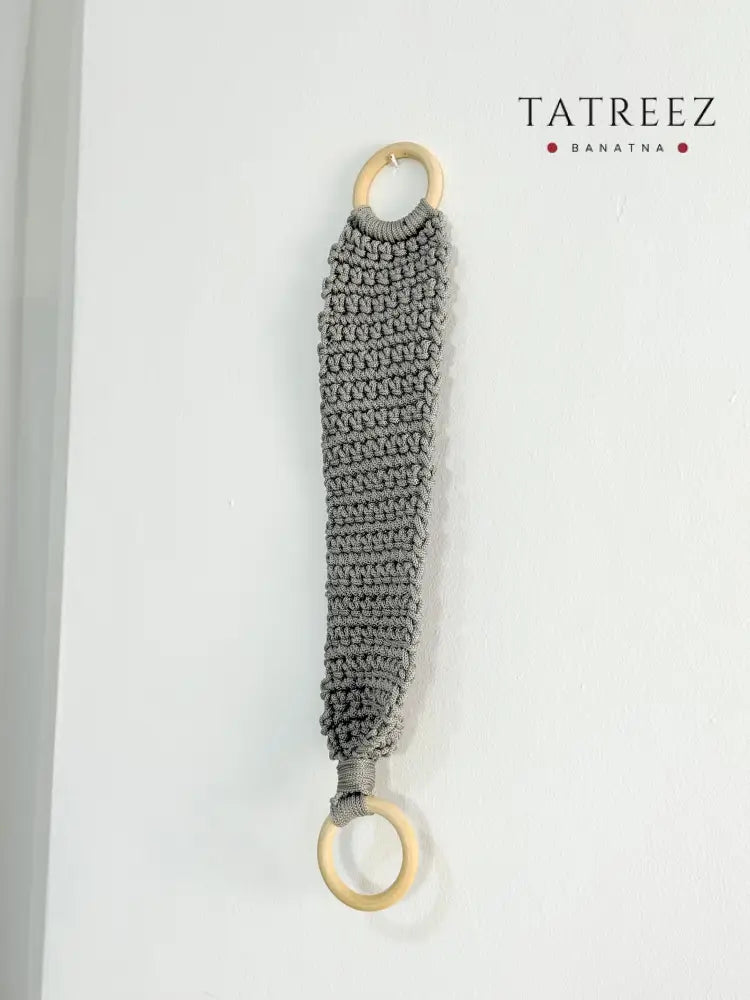 Handmade crochet kitchen towel hanger in soft grey with wooden rings, crafted by Palestinian women artisans for boho kitchen decor.