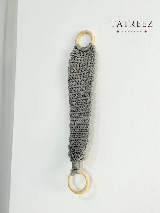Handmade crochet kitchen towel hanger in soft grey with wooden rings, crafted by Palestinian women artisans for boho kitchen decor.