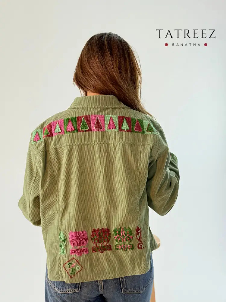 A light green denim jacket featuring beautiful handmade colorful embroidery on the back, showcasing unique artisan style and craftsmanship.