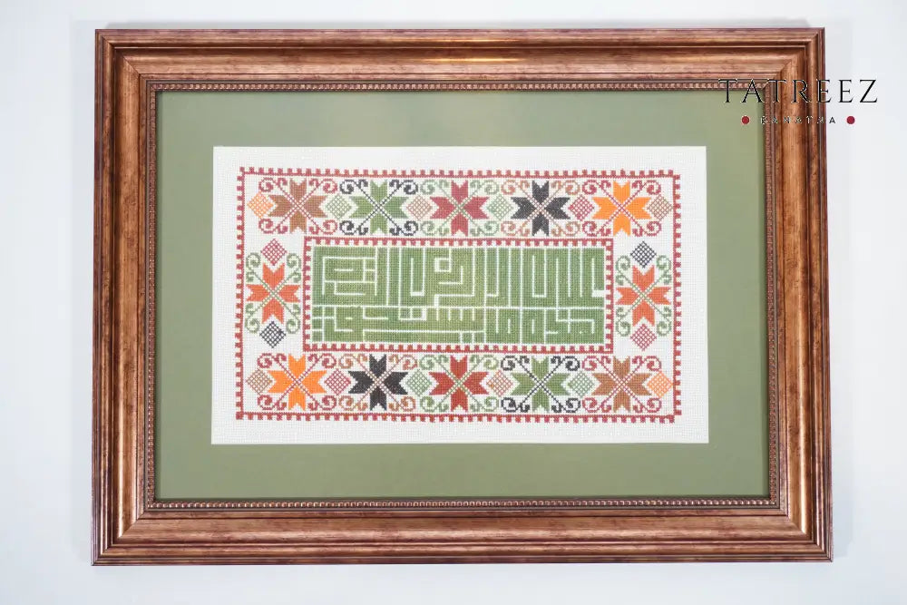 Handmade Palestinian tatreez framed artwork with “على هذه الأرض ما يستحق الحياة” (On this land, there is what deserves life), floral embroidery in orange, green, and black, symbolizing hope, beauty, and homeland