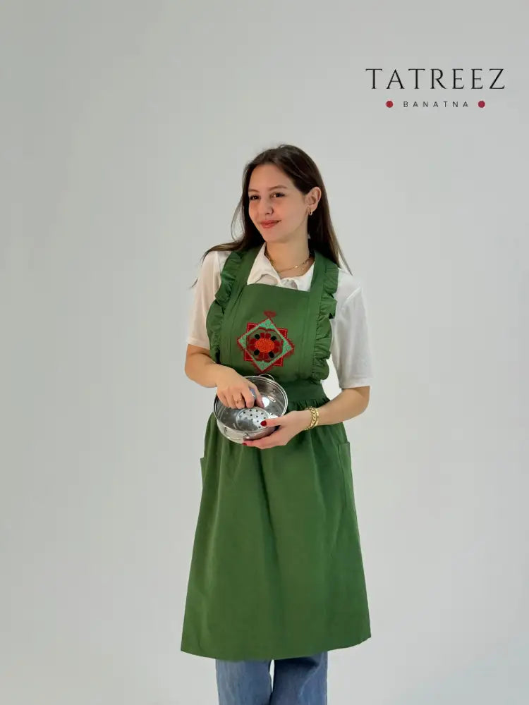 Handmade green waterproof apron with floral embroidery, crafted by Palestinian women artisans, perfect for kitchen and cooking use.