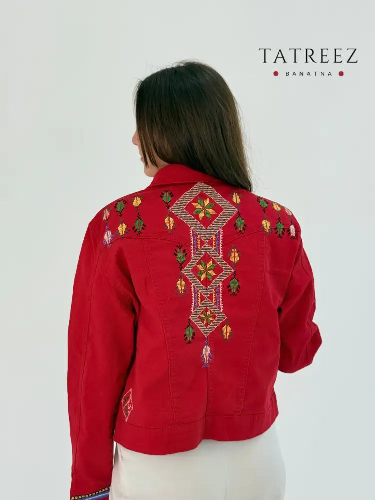Red jeans jacket with blue, orange, and green embroidery on the front and back, showcasing a vibrant and stylish design.