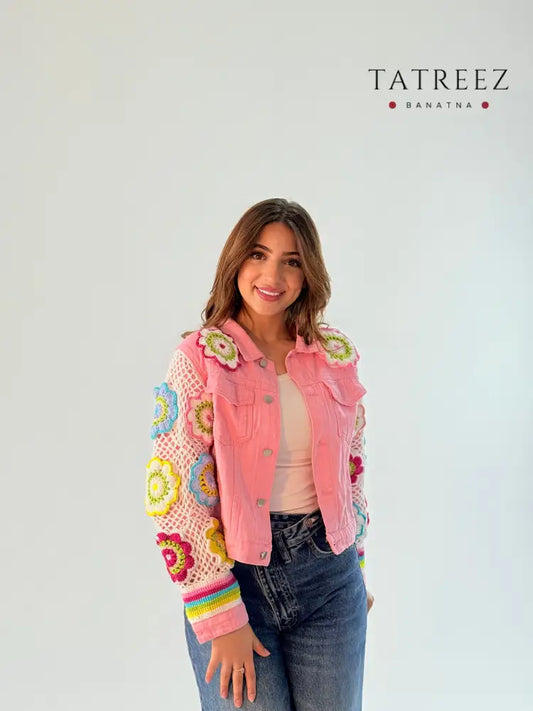 Pink jeans jacket with crochet work on the sleeves and floral accents on the front pockets, showcasing a stylish and feminine design.
