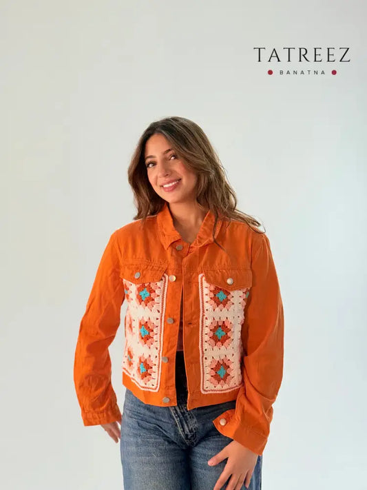 Orange denim jacket featuring handmade crochet grannies in vibrant turquoise and white, modeled by a woman wearing a size large.